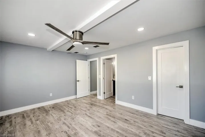 Unfurnished bedroom with ceiling fan, light hardwood / wood-style floors, and beamed ceiling