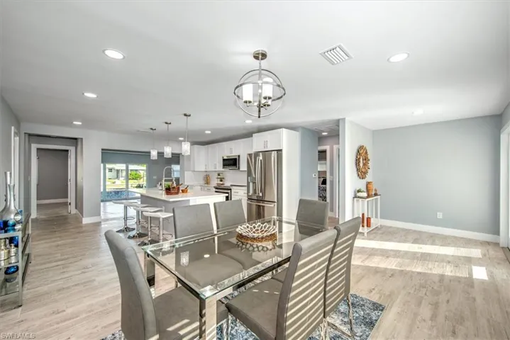 Dining space featuring sink, light wood-type flooring, and a notable chandelier