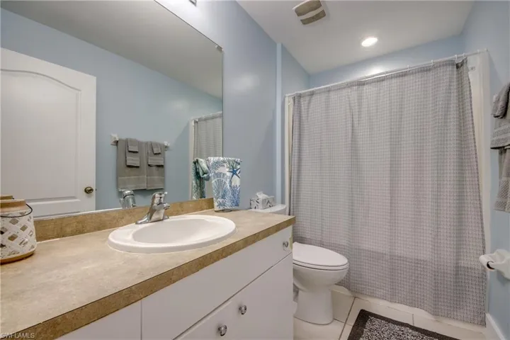 Bathroom with shower / tub combo with curtain, vanity, light tile patterned floors, and recessed lighting