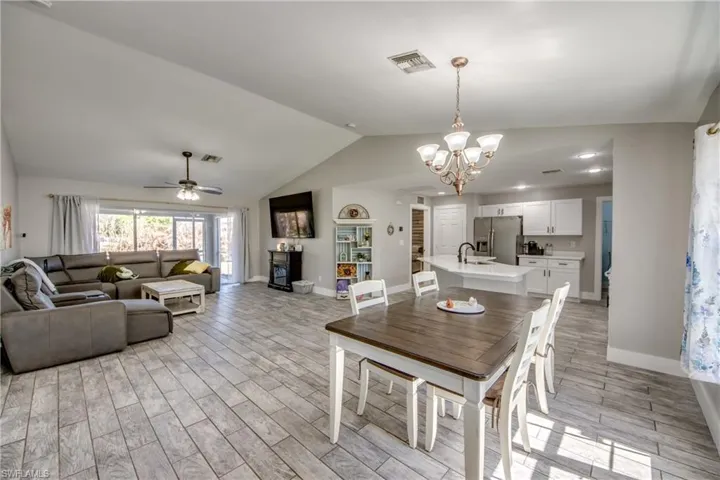 Dining area with ceiling fan, wood finish floors, hanging lights, and a fireplace