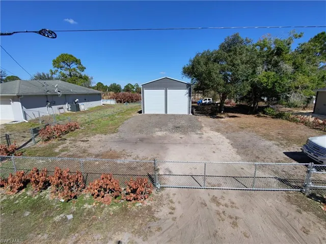 View of yard with a garage, an outdoor structure, driveway, and a gate