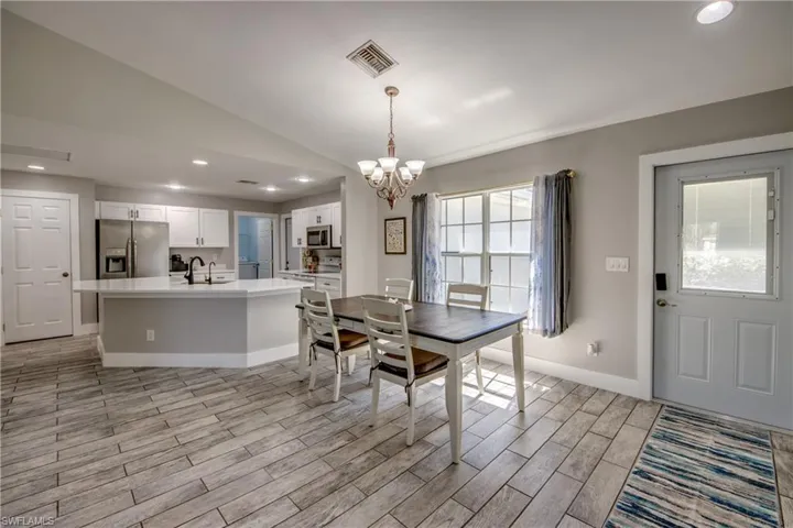 Dining room featuring vaulted ceiling, wood finish floors, and a chandelier