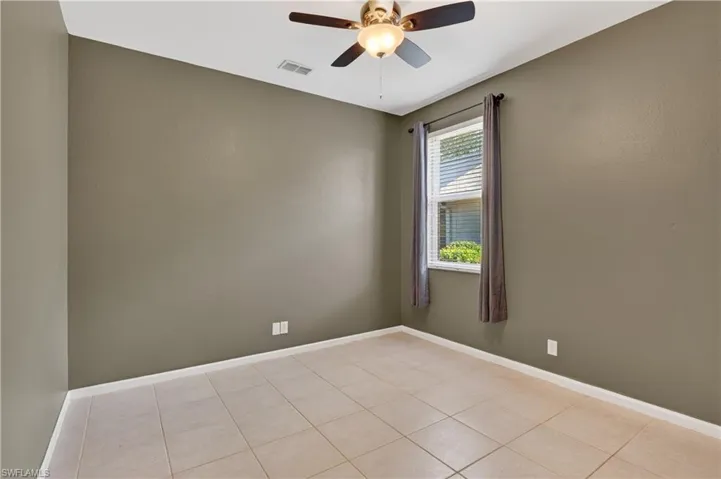 Empty room with ceiling fan and light tile patterned flooring