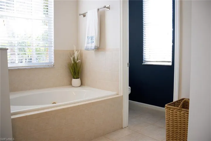 Full bath featuring a stall shower, a jetted tub, vanity, and tile patterned floors