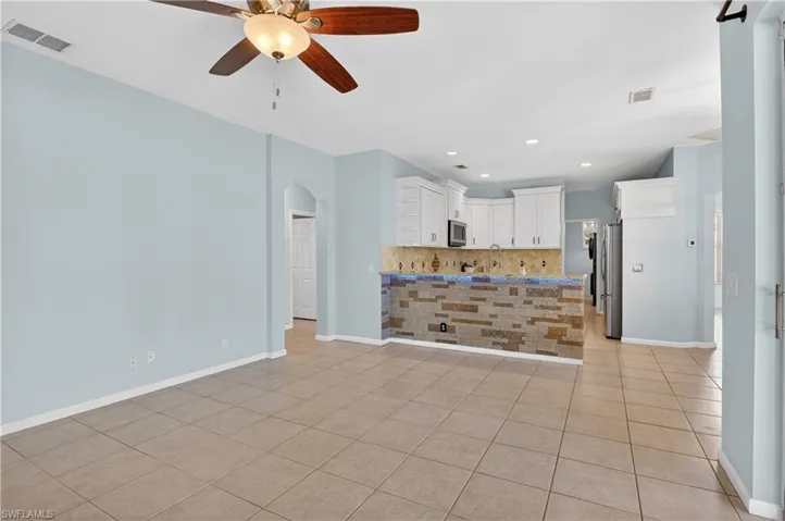 Kitchen featuring arched walkways, ceiling fan, light tile patterned floors, recessed lighting, and white cabinetry