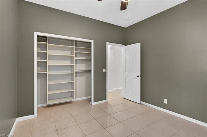 Unfurnished bedroom with ceiling fan, a closet, and light tile patterned floors
