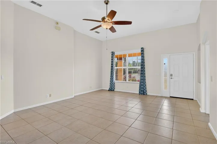 Unfurnished room featuring a ceiling fan, light tile patterned flooring, and arched walkways