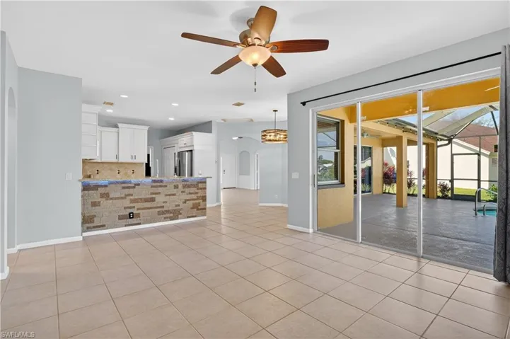 Unfurnished living room with arched walkways, a ceiling fan, recessed lighting, and light tile patterned floors