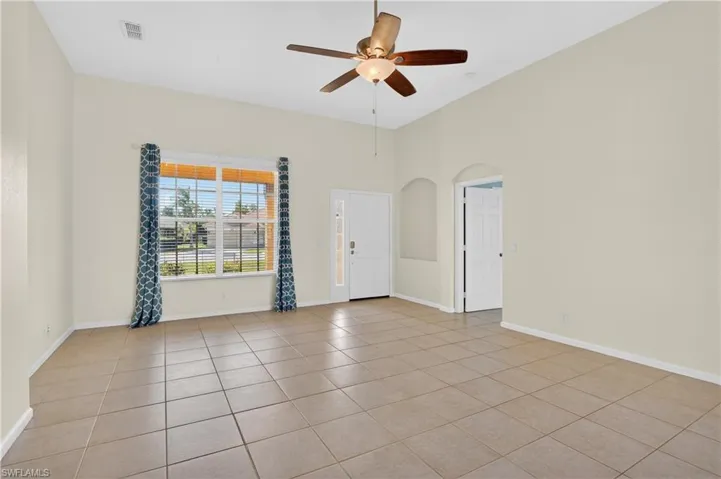 Spare room with arched walkways, a ceiling fan, and light tile patterned flooring