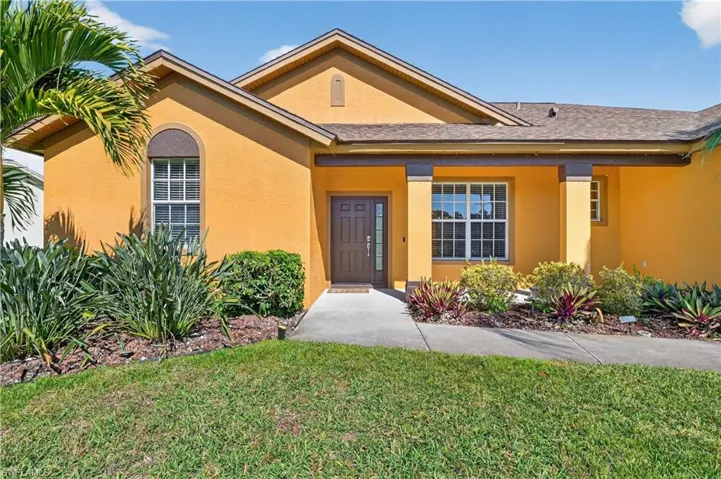 Entrance to property with stucco siding and a yard