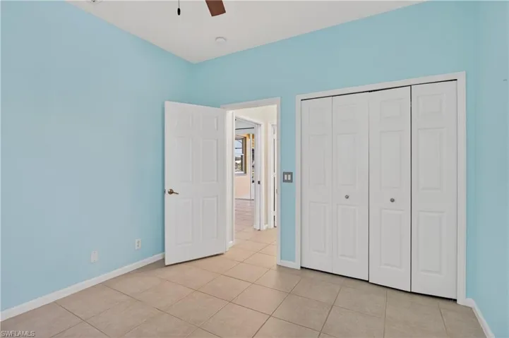 Guest suite bedroom with a ceiling fan, light tile patterned floors, and a closet