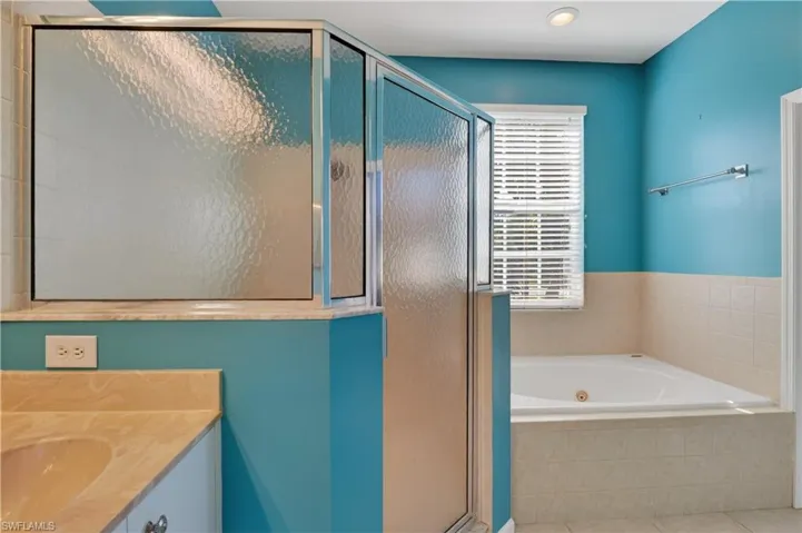 Full bath featuring a stall shower, a jetted tub, vanity, and tile patterned floors