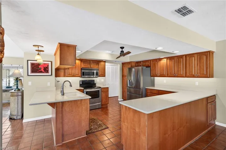 Warm wood cabinets, solid surface countertops and stainless appliances are found in the kitchen.