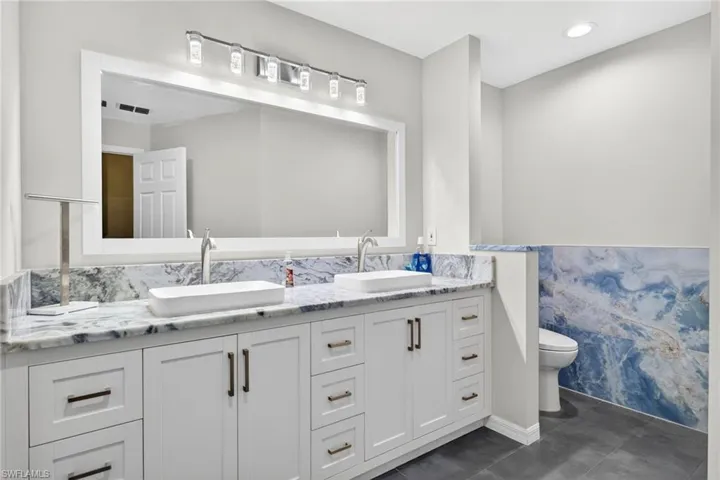 The beautifully remodeled primary bathroom features a modern double vanity with dual vessel sinks, sleek fixtures, and abundant storage.