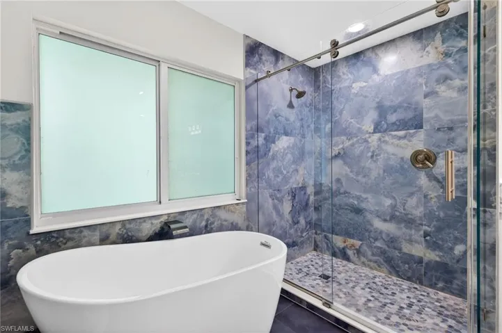 The spa inspired remodeled primary ensuite bathroom, with a frameless barn door sliding glass shower enclosure and a freestanding soaking tub.