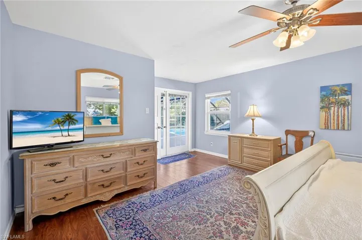 French doors in the primary bedroom provide access to the pool and screened in lanai.