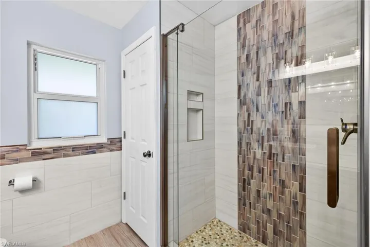 The updated walk-in shower features a frameless glass enclosure while the neutral tones and quality finishes offer a spa-like feel.
