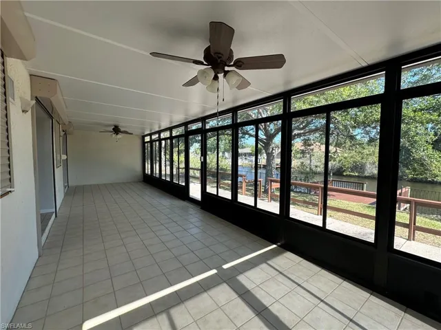 Unfurnished sunroom with ceiling fan and tile patterned flooring