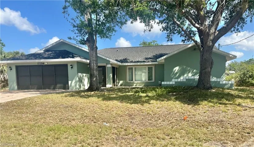 Single story home featuring a garage, stucco siding, a front lawn, and driveway