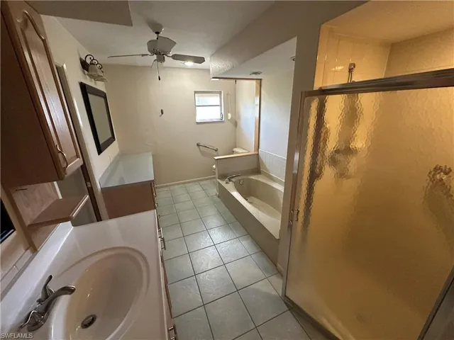 Bathroom with tile patterned floors, vanity, a bath, a ceiling fan, and a shower stall