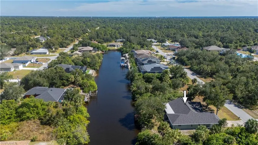 Aerial perspective of suburban area with a large body of water and a forest