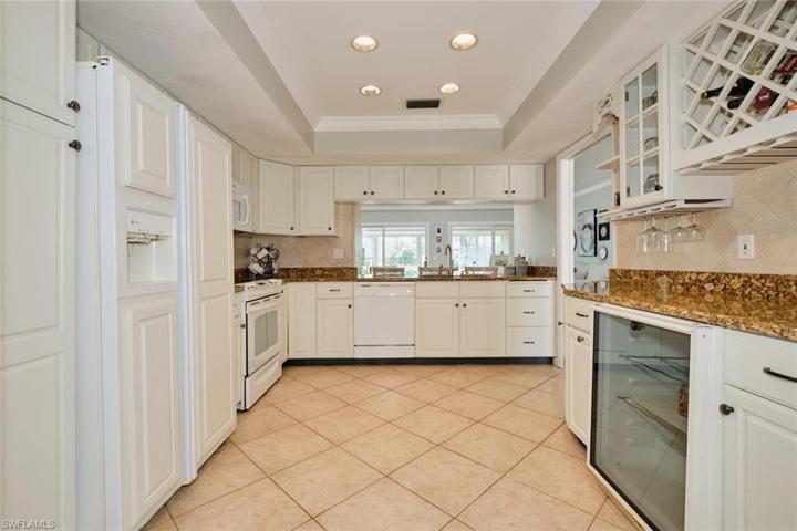 Kitchen features tile floors, granite tops, white cabinetry.