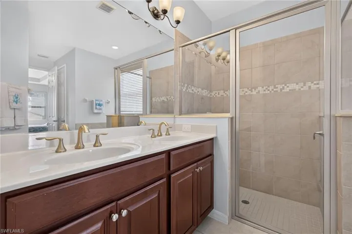 Dual vanity with white countertops, undermount sinks, and brass-finish fixtures