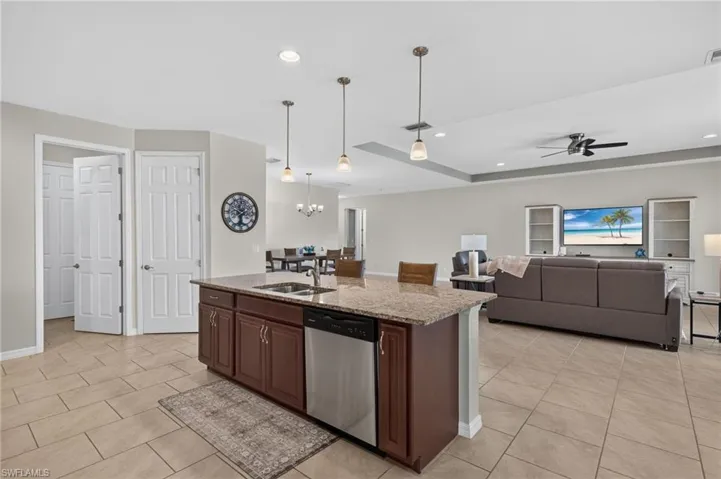 Kitchen island with granite countertop, integrated sink, and stainless steel dishwasher