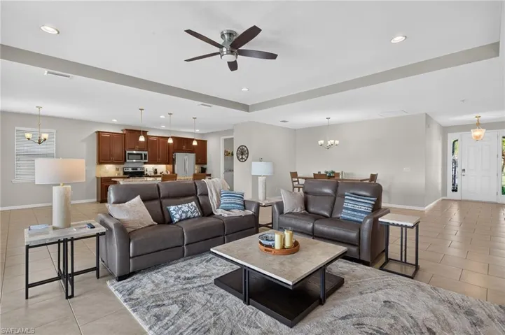 Open-concept living space featuring neutral tile flooring, recessed lighting, and a ceiling fan