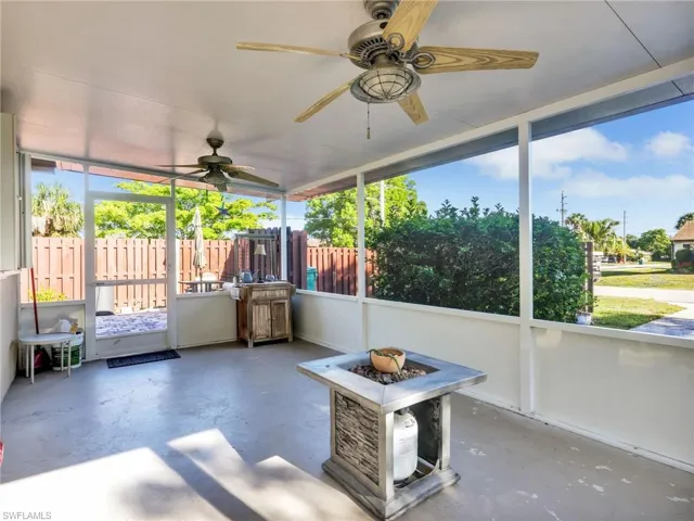 Spacious screened lanai featuring two ceiling fans, a concrete floor, and a built-in fire pit