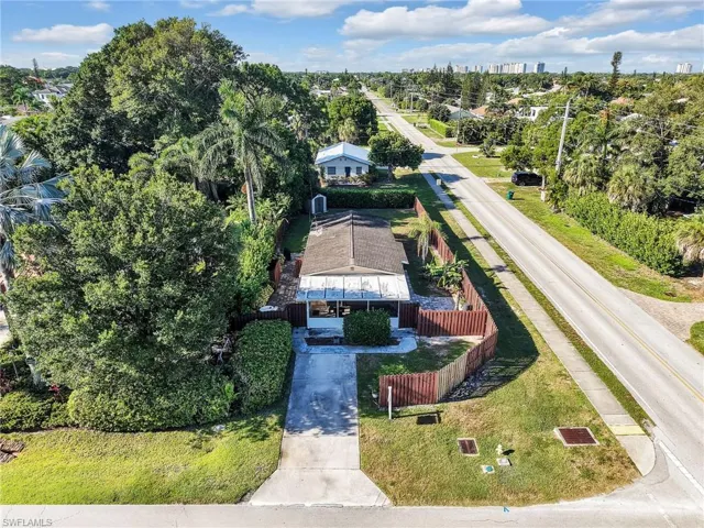 Aerial perspective showcasing the property with lush landscaping, a private fenced yard, and an extended driveway