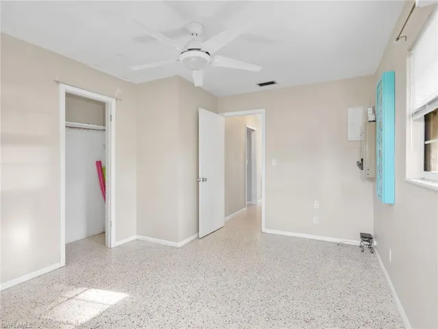 Neutral-toned interior room featuring terrazzo flooring, a white ceiling fan with integrated lighting, and a window with blinds