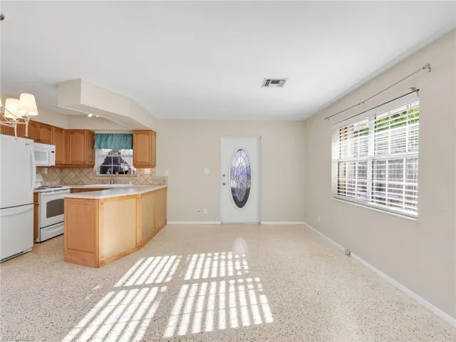 Kitchen area featuring wood cabinetry, white appliances, and a tiled backsplash