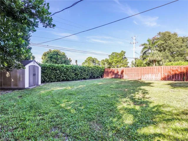 Expansive lawn area featuring a storage shed with white trim and gray double doors