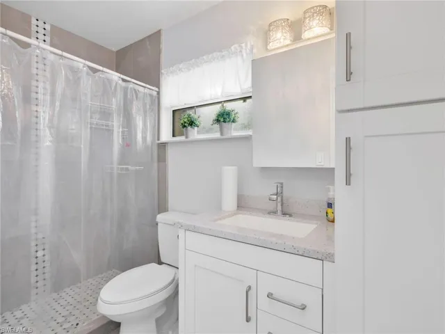 Full bathroom featuring a shower with tiled surround, a white vanity with an undermount sink and light-toned countertop, and a built-in storage cabinet
