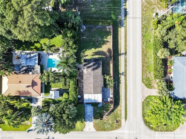 Aerial perspective highlighting the property's rectangular lot with mature trees and a paved driveway