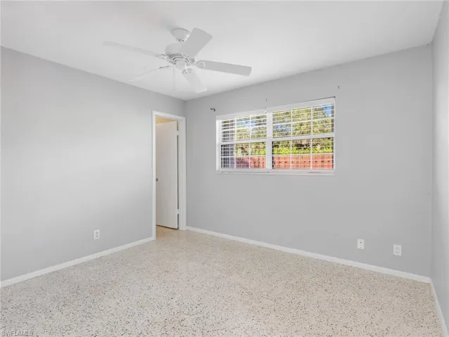 Spacious room featuring light gray walls, a ceiling fan with integrated lighting, and a window with horizontal blinds
