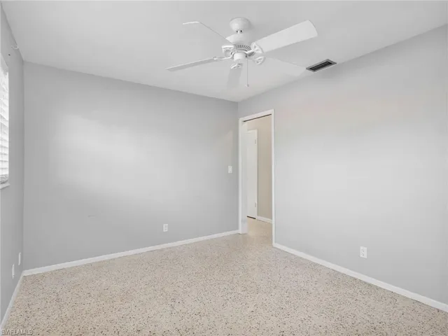 Bright interior space featuring light gray walls, a white ceiling fan, and speckled terrazzo flooring