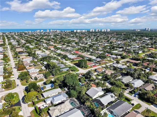 Expansive aerial showcasing a residential neighborhood with numerous single-story homes, mature trees, and visible street infrastructure