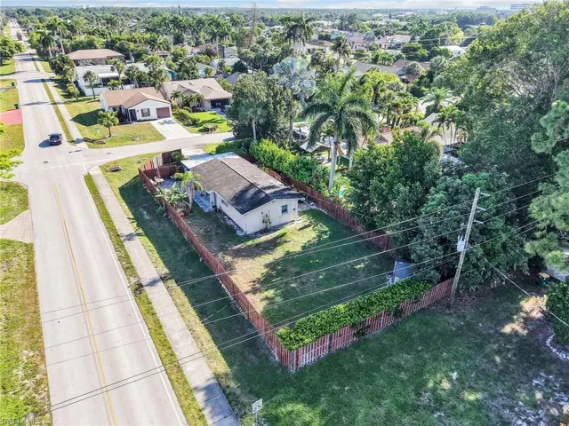 Corner lot property featuring a fenced yard with mature trees and established landscaping