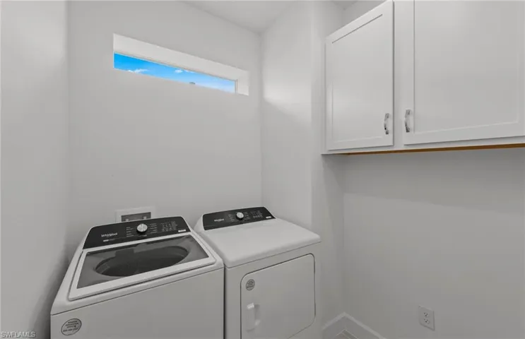 Clothes washing area with washer and dryer, cabinets, and washer hookup