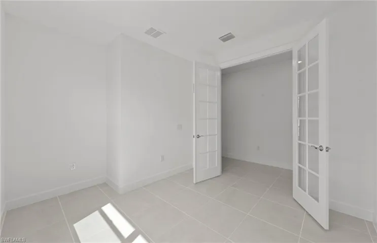 Unfurnished bedroom with french doors and light tile floors