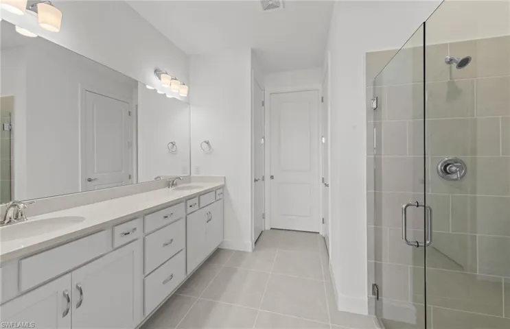 Bathroom with a shower with door, tile flooring, and dual vanity