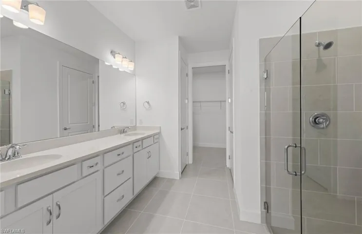 Bathroom featuring walk in shower, tile floors, oversized vanity, and dual sinks