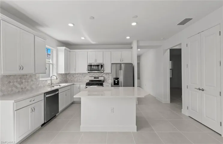 Kitchen with a center island, sink, light tile floors, and stainless steel appliances