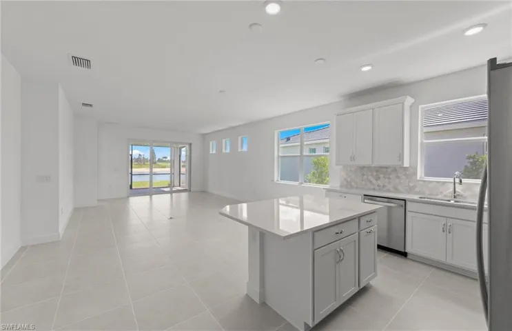 Kitchen with a center island, appliances with stainless steel finishes, sink, tasteful backsplash, and light tile flooring