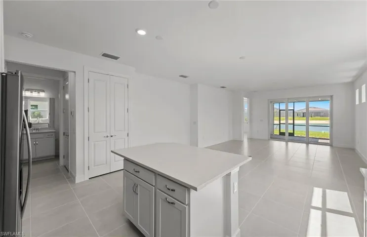 Kitchen featuring a water view, gray cabinets, light tile floors, a center island, and stainless steel refrigerator