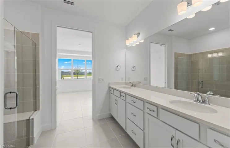 Bathroom with walk in shower, double sink, tile floors, and large vanity