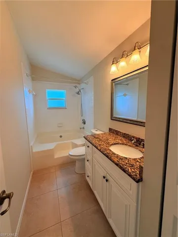 Bathroom featuring vaulted ceiling, shower / bath combination, vanity, and light tile patterned flooring