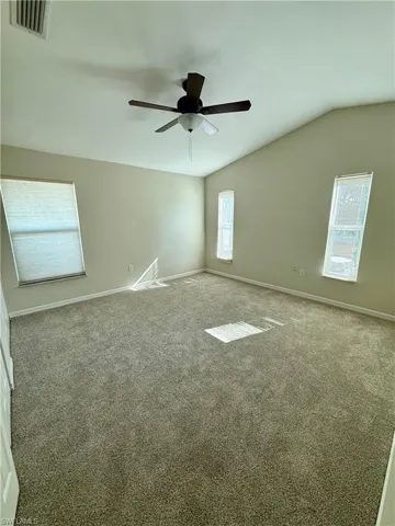 Carpeted master room with vaulted ceiling and baseboards